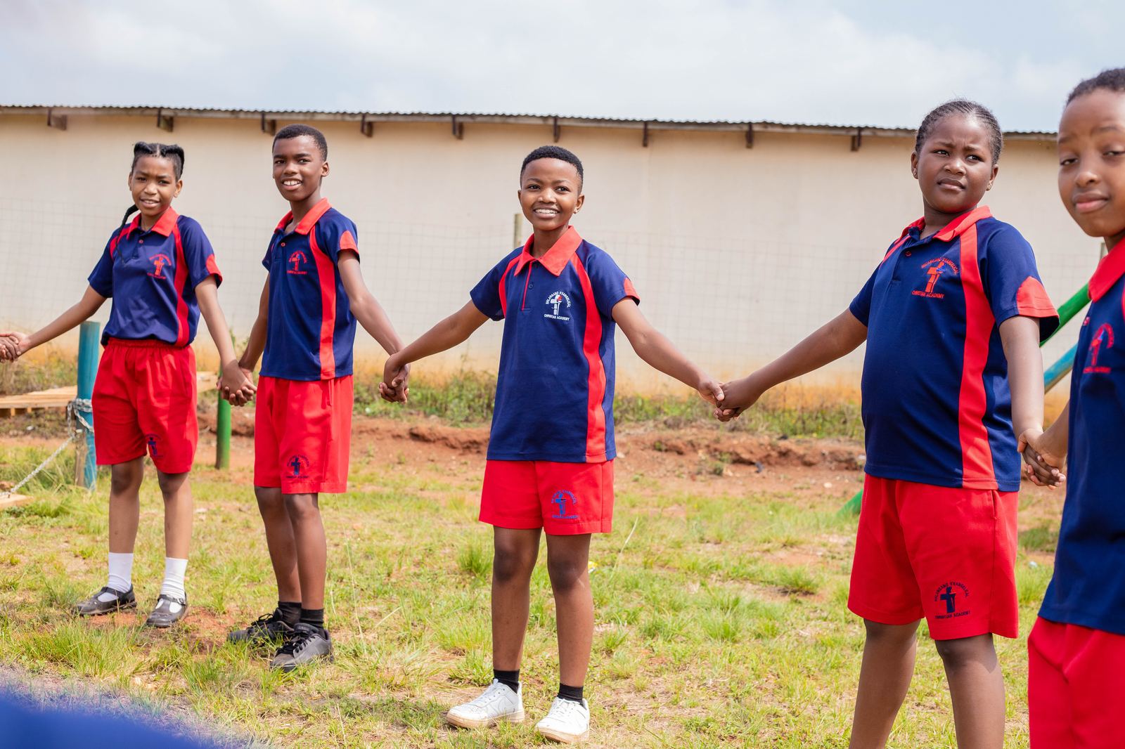 NECA pupils holding hands together on the school field