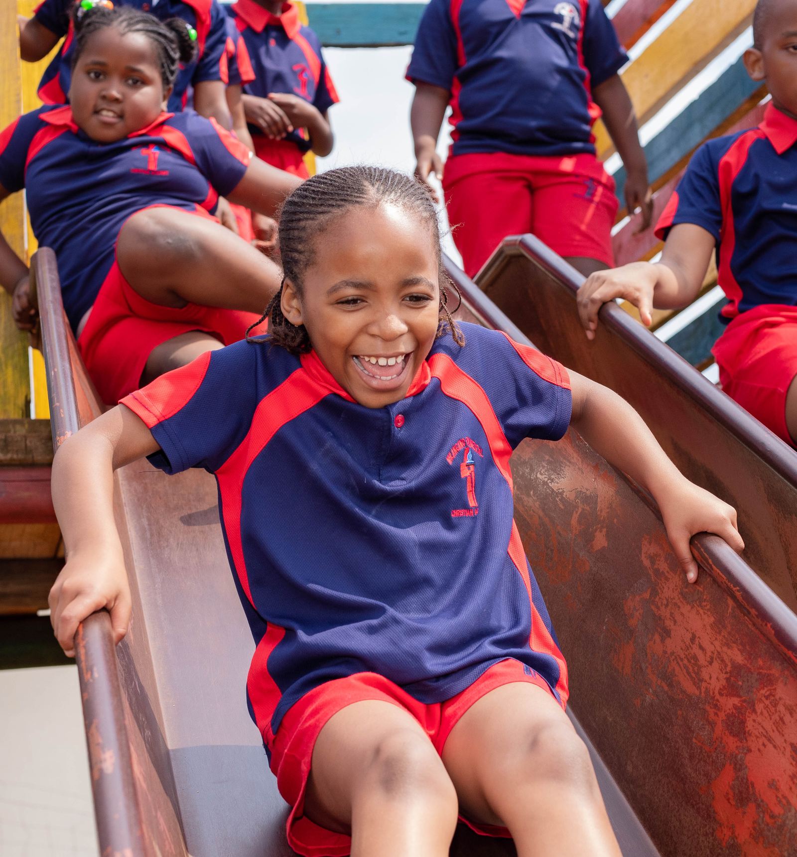 A joyful NECA pupil in school uniform playing on the school playground